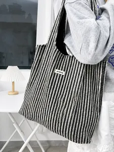 Detail of large tote bag showing black and white herringbone fabric and branded label