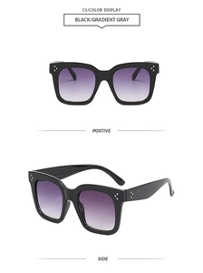 Détail de lunettes de soleil carrées noires avec clous argentés en étoile et verres dégradés