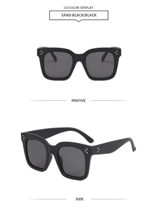 Détail de lunettes de soleil carrées noires avec rivets argentés à trois points iconiques