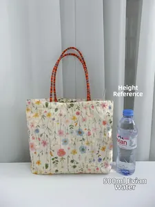 Floral canvas tote bag size comparison with 500ml water bottle and silver button detail