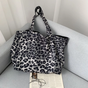 Detail of leopard print tote bag on a sofa with newspaper and glasses lifestyle setup