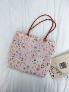 Detailed macro view of pink canvas bucket bag with floral embroidery and magnetic closure