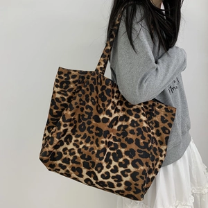 Macro shot of large leopard print canvas tote bag with wide shoulder strap on model