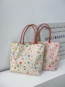 Detail of floral embroidery and woven handles on cream and pink canvas bucket bags