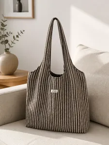 Detail showing the brown and white striped woven texture and ATRYG brand label of the tote bag