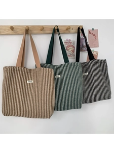 Detail of herringbone wool tote bags in brown, green, and black with woven handles