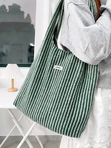 Detail of ATRYG knitted tote bag with green and white herringbone pattern and logo