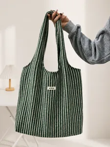 Detail of green herringbone wool tote bag featuring a brand label and large capacity