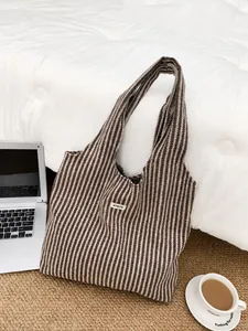 Close-up of brown herringbone wool tote bag with ATRYG label on a white bed