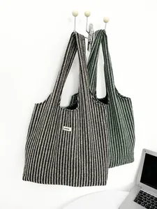 Detail of herringbone wool tote bags in black and green colors hanging on a hooks