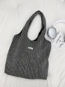 Close-up of black and white herringbone wool tote bag with ATRYG label and long handle
