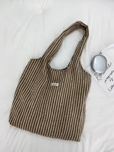 Detailed top view of herringbone wool tote bag with ATRYG label and silver headphones