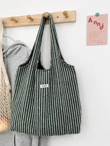 Detailed view of green and cream herringbone wool tote bag with ATRYG label on a wooden hook
