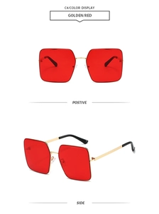 Detail view of square gold metal sunglasses with red lenses and black temple tips