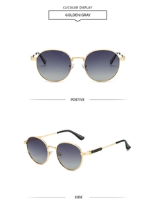 Detail view of oval sunglasses with gold metal frames and grey gradient lenses