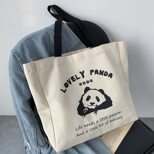 Detail of a beige canvas tote bag featuring a cute panda illustration on a denim jacket
