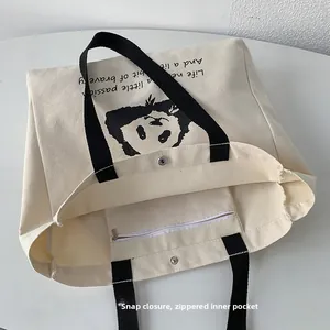 Detail view of canvas tote featuring panda print, metal snap closure, and inner zipper pocket