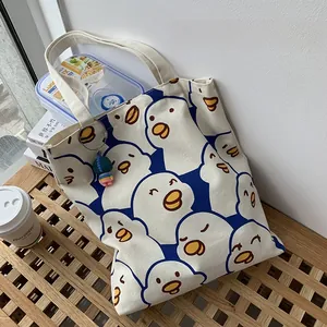 Close-up of canvas tote bag with cartoon duck pattern and colorful doll pendant