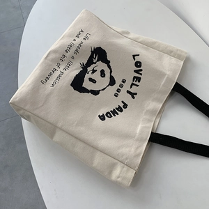 Detail of cute panda canvas tote bag with black handles and inspirational text print