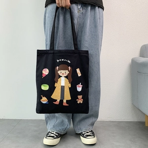 Detail of black canvas tote bag with colorful cartoon girl print and cute lettering