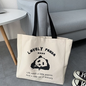 Detail of cute panda printed canvas tote bag with black handles in a home setting
