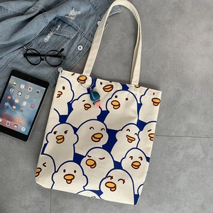 Detail of canvas tote bag featuring cute cartoon duck print and colorful fish charm