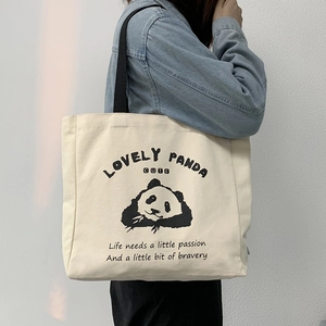 Detail of off-white canvas tote bag featuring cute panda illustration and black straps