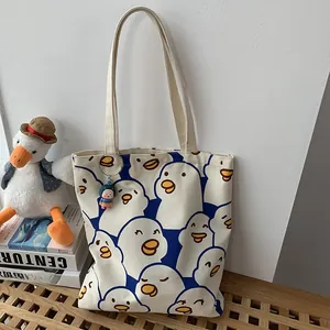 Detail of canvas tote bag with cartoon duck print and a cute striped doll pendant
