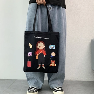 Detail view of a black canvas tote bag featuring cute cartoon girl illustrations