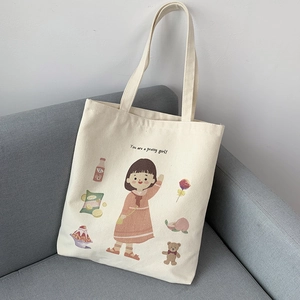 Detail view of canvas tote bag with cute cartoon girl illustration on a gray sofa