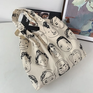 Close-up of minimalist canvas tote bag featuring artistic black line illustrations of faces