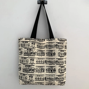 Detail of canvas tote bag featuring minimalist black text print and nylon straps