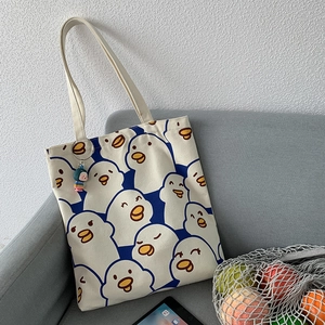 Detail of canvas tote bag with cartoon duck prints and cute character pendant accessory