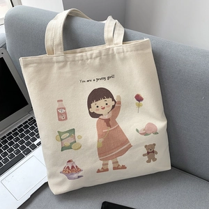 Detail of canvas tote bag showing cute cartoon girl illustration and slogan on sofa