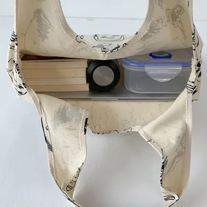 Top view showing the large capacity of a beige canvas tote bag with books and a water bottle