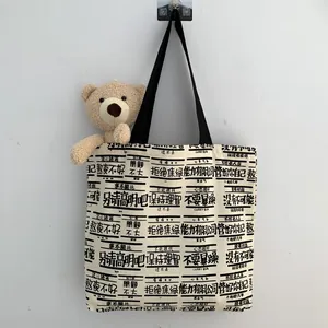 Vertical view of canvas tote with text prints and a brown teddy bear accessory