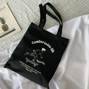 Detail of black canvas tote bag with skateboarder illustration and letter print
