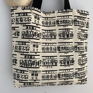Detail of canvas tote bag with funny black text prints and durable black handles