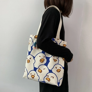 Detailed view of canvas tote bag with blue cartoon duck print and colorful pendant