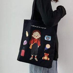 Detailed view of black canvas tote bag with cute cartoon girl print shown on model