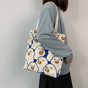 Detailed view of canvas tote bag featuring cute duck pattern and colorful doll pendant