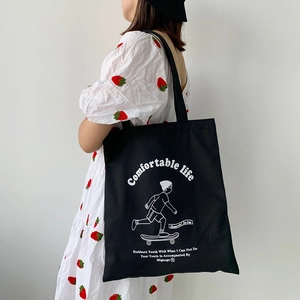 Detail of black canvas tote bag with skater print and Comfortable Life text