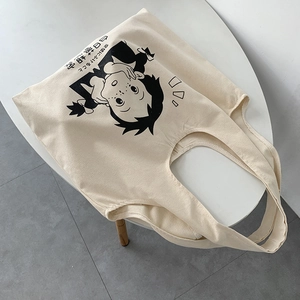 Gros plan d'un sac fourre-tout en toile beige avec imprimé manga rétro sur table blanche