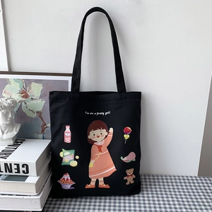Detail of a black canvas tote bag featuring a cute cartoon girl and snacks illustration