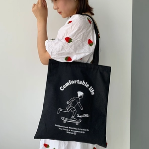 Detail of black canvas tote bag with white lettering and graphic on a female model