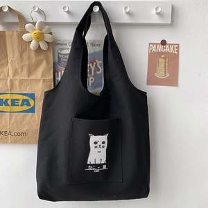 Close-up of black canvas tote bag featuring cute cat print and a functional front pocket