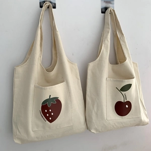 Detail view of canvas tote bags featuring front pockets with strawberry and cherry prints