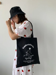 Close-up of black canvas tote bag with skateboarder print and Comfortable Life text
