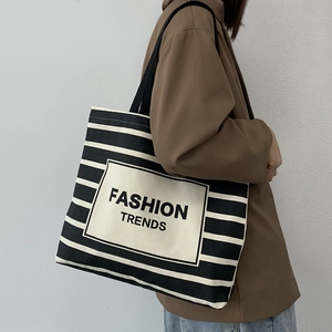 Close-up of black and white striped canvas tote bag with Fashion Trends patch detail