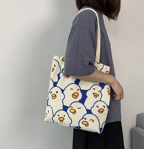 Detail of a large white canvas tote bag with a cute all-over blue cartoon duck pattern